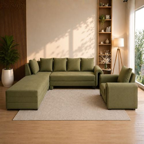 An olive green sectional sofa with matching armchair in a modern, warm-toned living room setting with a light beige rug, wooden floor, and built-in shelving.