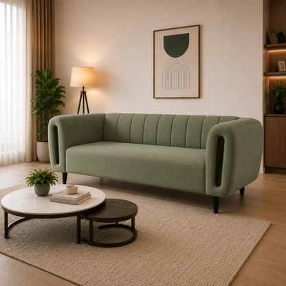 A modern sage green velvet sofa with channel tufting and integrated side cutouts, styled in a warm, contemporary living room with a beige rug, wooden coffee tables, and a floor lamp.